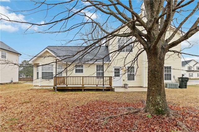 rear view of property with central AC, a deck, and a lawn