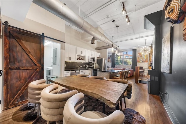 dining area with hardwood / wood-style flooring, a notable chandelier, a barn door, and sink