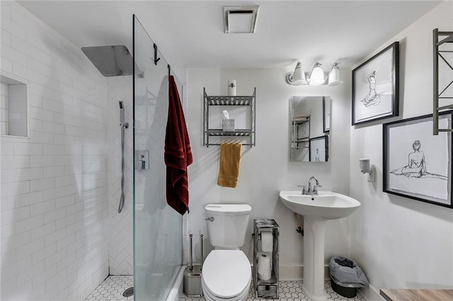 bathroom featuring tiled shower, tile patterned floors, toilet, and sink