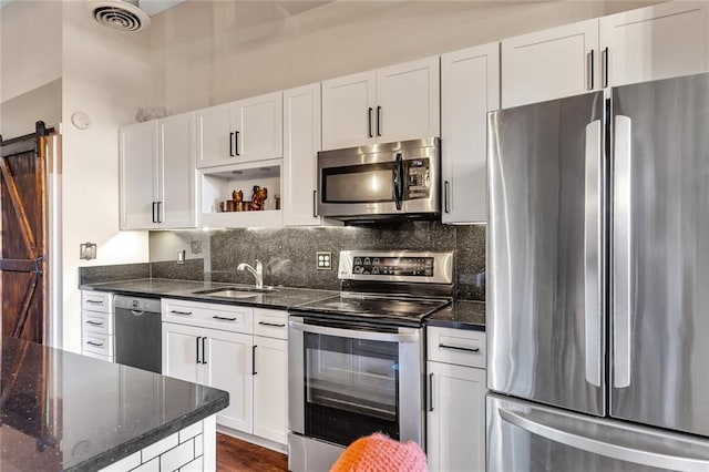 kitchen with white cabinets, appliances with stainless steel finishes, a barn door, and sink