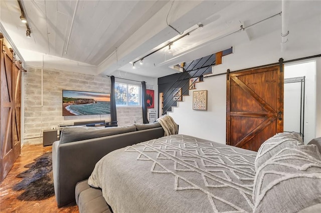 bedroom featuring hardwood / wood-style floors, a barn door, and rail lighting