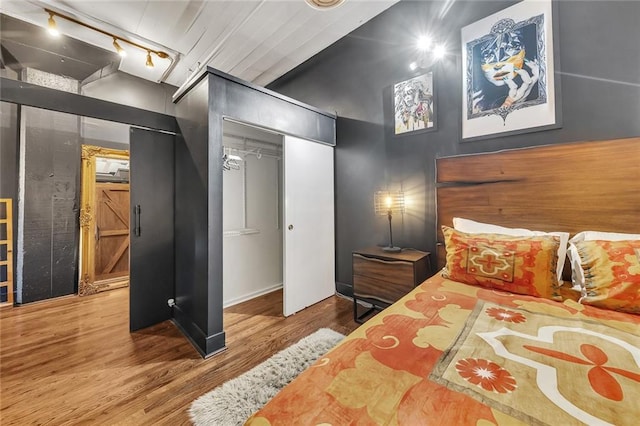 bedroom featuring rail lighting, hardwood / wood-style flooring, and a closet