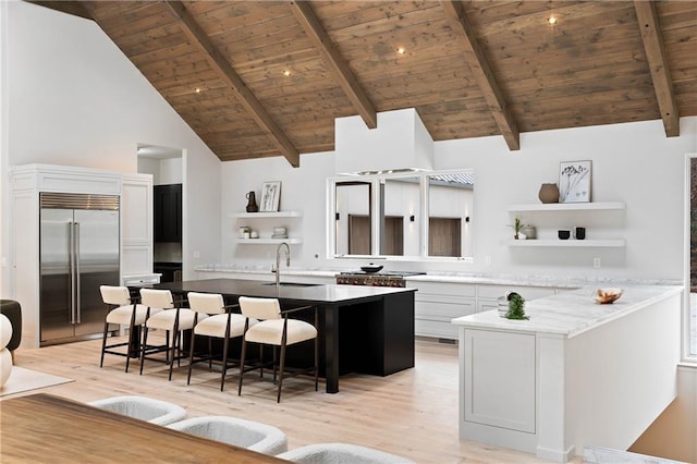 kitchen with a kitchen breakfast bar, beam ceiling, stainless steel built in fridge, wooden ceiling, and white cabinetry