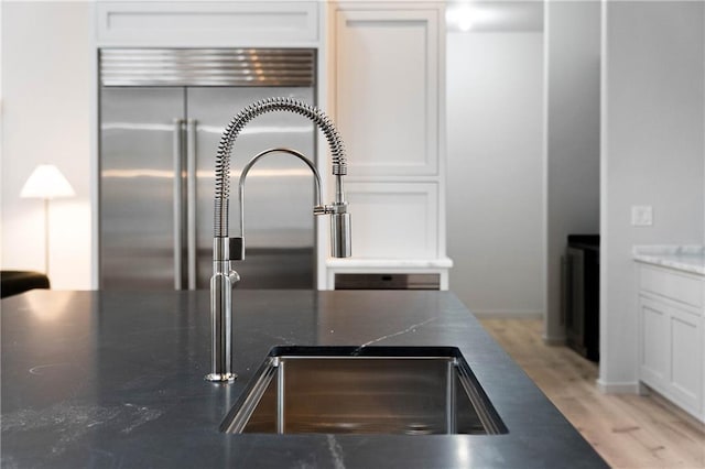 room details with white cabinetry, stainless steel built in fridge, and sink