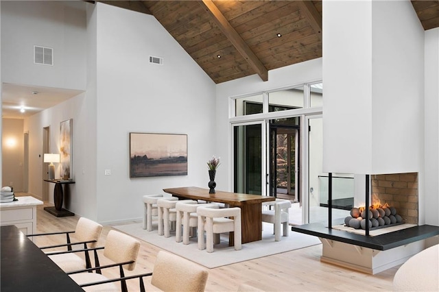 dining room featuring beam ceiling, light hardwood / wood-style flooring, high vaulted ceiling, and wooden ceiling