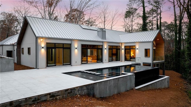 back house at dusk featuring a patio