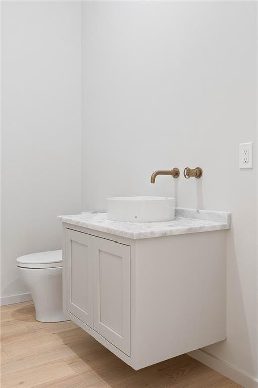 bathroom with hardwood / wood-style floors, vanity, and toilet