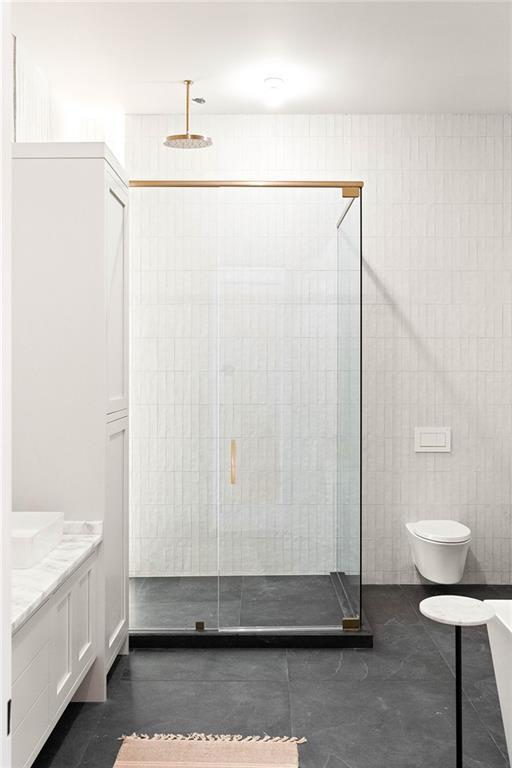 bathroom with vanity, toilet, tile walls, and a shower with shower door