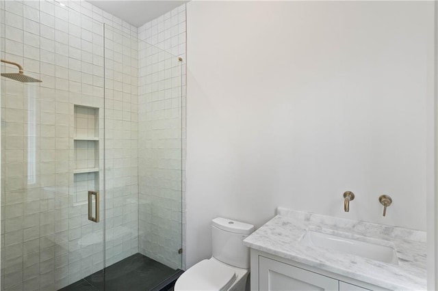 bathroom featuring a shower with door, vanity, and toilet