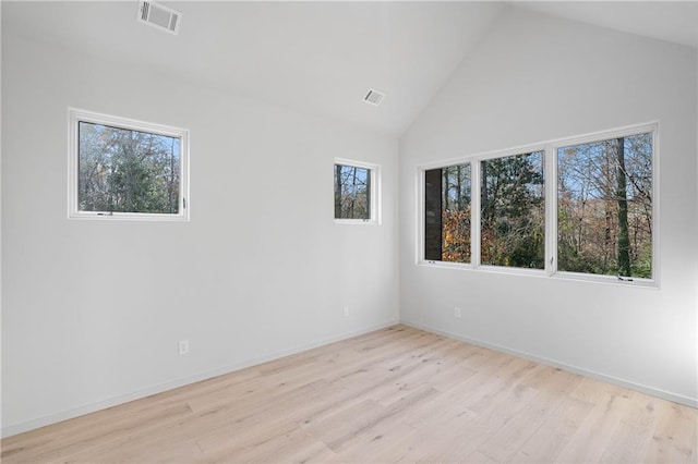 empty room with light hardwood / wood-style flooring, a healthy amount of sunlight, and lofted ceiling