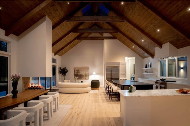 living room featuring beam ceiling, sink, wooden ceiling, high vaulted ceiling, and light hardwood / wood-style floors