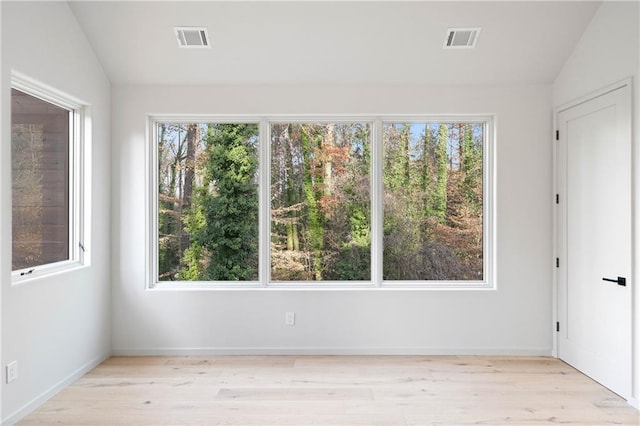 spare room featuring light wood-type flooring and vaulted ceiling