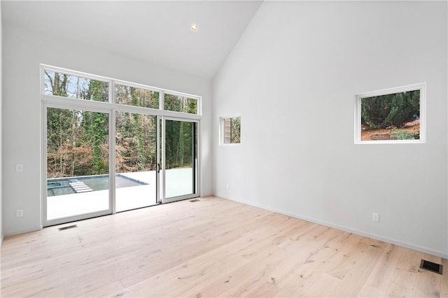 empty room featuring light hardwood / wood-style flooring and high vaulted ceiling