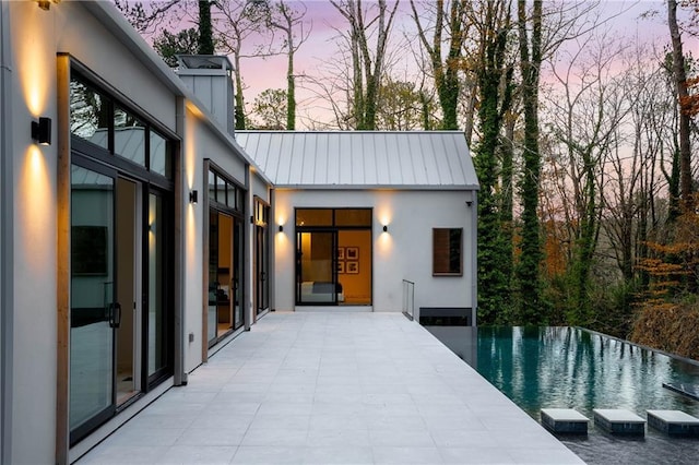 pool at dusk featuring a patio area