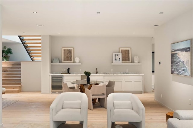 dining room with bar area, light hardwood / wood-style flooring, and beverage cooler