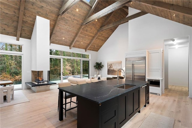 kitchen with a center island with sink, sink, high vaulted ceiling, and built in refrigerator