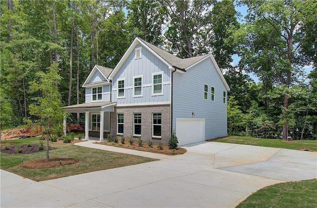 view of front of property featuring a front lawn, board and batten siding, concrete driveway, a garage, and brick siding