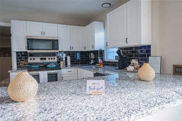 kitchen featuring appliances with stainless steel finishes, light stone counters, and white cabinets