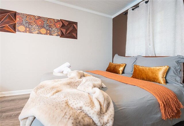 bedroom with ornamental molding, baseboards, and wood finished floors