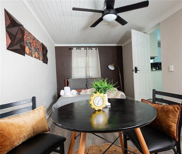 dining room with wooden ceiling, wood finished floors, a ceiling fan, and crown molding