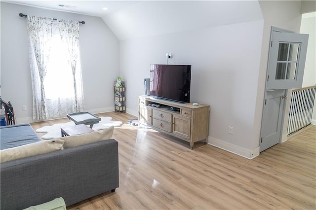 living area featuring baseboards, lofted ceiling, visible vents, and light wood-style flooring