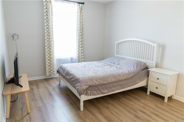 bedroom featuring light wood-style floors and baseboards