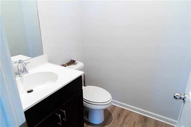 bathroom featuring vanity, toilet, wood finished floors, and baseboards