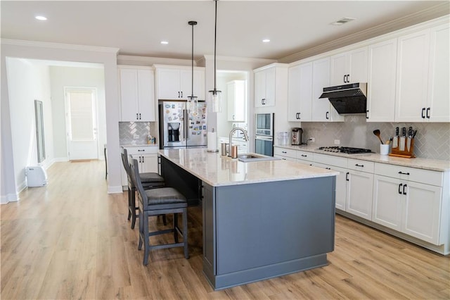 kitchen with extractor fan, light wood-type flooring, a kitchen breakfast bar, appliances with stainless steel finishes, and a sink