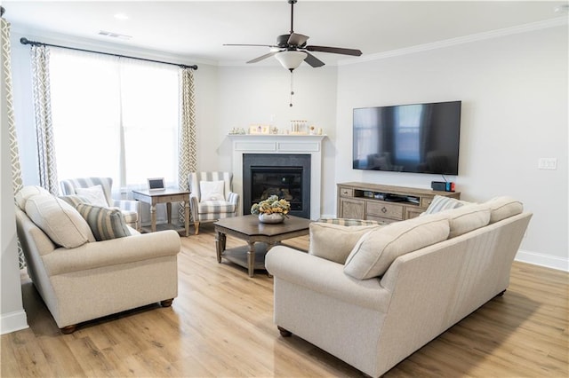 living room with visible vents, baseboards, light wood-style floors, and ornamental molding