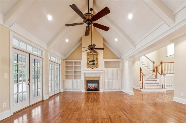 unfurnished living room with beam ceiling, french doors, high vaulted ceiling, hardwood / wood-style floors, and a fireplace