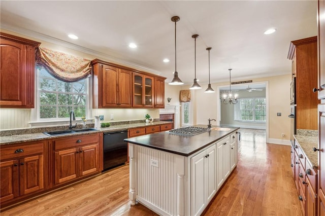 kitchen with appliances with stainless steel finishes, ornamental molding, sink, pendant lighting, and light hardwood / wood-style floors