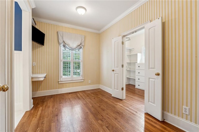 220 Spring Branch Dr, Canton, GA 30115 - unfurnished bedroom featuring wood finished floors, crown molding, wallpapered walls, a walk in closet, and baseboards
