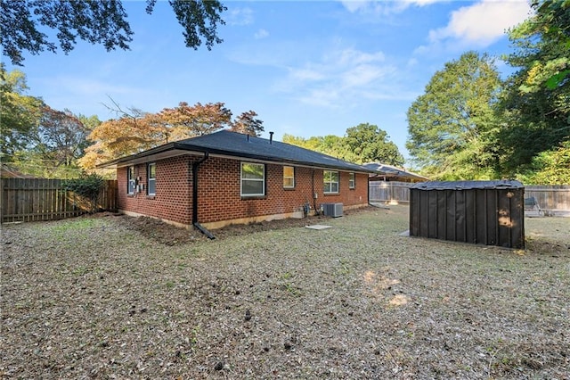 rear view of property featuring cooling unit and a storage shed