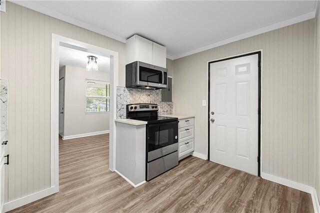 kitchen featuring ornamental molding, light hardwood / wood-style floors, stainless steel appliances, white cabinets, and decorative backsplash