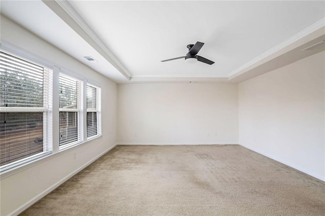 spare room with ceiling fan, a raised ceiling, and light carpet