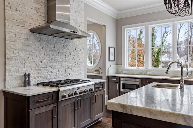 kitchen featuring wall chimney range hood, crown molding, sink, stainless steel appliances, and light stone counters