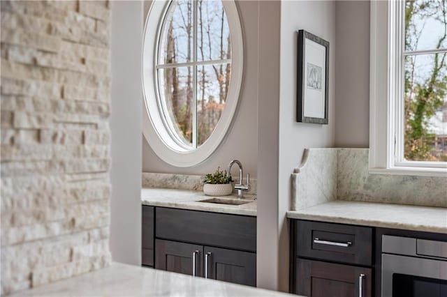 interior space with light stone countertops, plenty of natural light, sink, and dark brown cabinetry