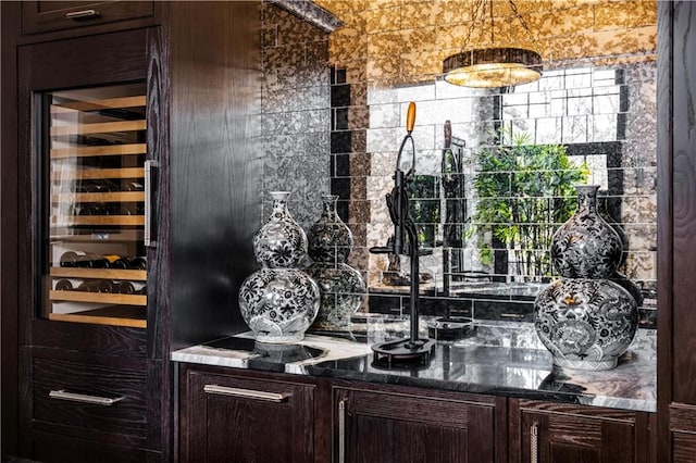 bar with dark brown cabinets, wine cooler, and dark stone counters