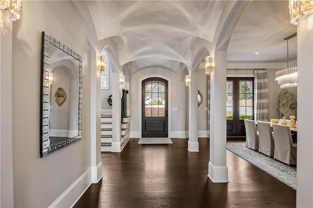 foyer entrance featuring an inviting chandelier, dark hardwood / wood-style floors, vaulted ceiling, and french doors