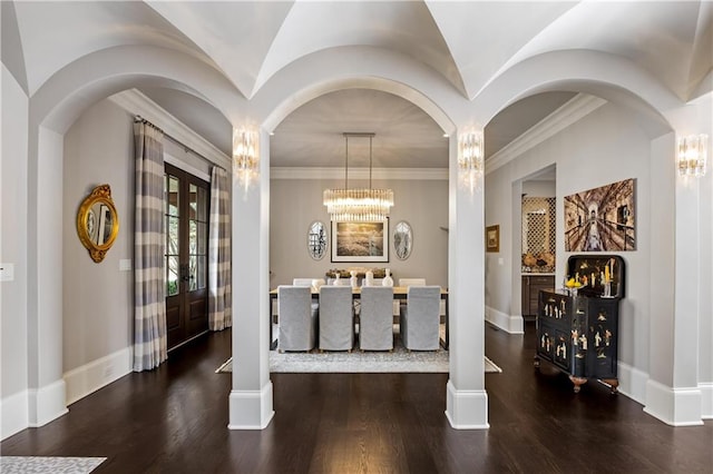 dining space featuring crown molding, dark wood-type flooring, an inviting chandelier, and french doors