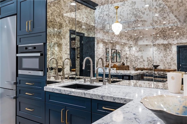 kitchen with appliances with stainless steel finishes, sink, and blue cabinetry