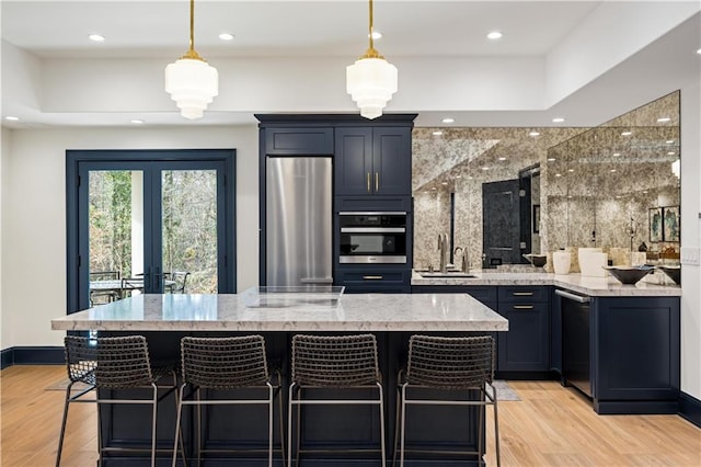 kitchen with light stone counters, sink, stainless steel appliances, and a kitchen bar