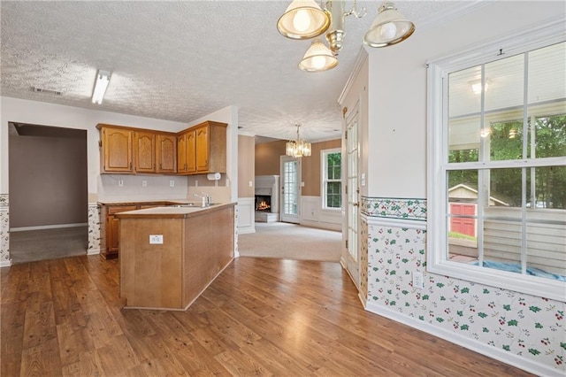 605 Pebble Blvd, Covington, GA 30016 - kitchen featuring a chandelier, brown cabinets, wood finished floors, wainscoting, and a peninsula