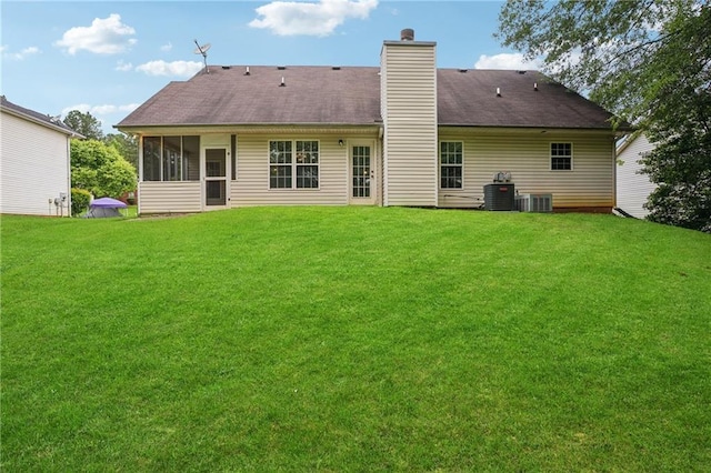 605 Pebble Blvd, Covington, GA 30016 - back of house featuring a lawn, central AC unit, a chimney, and a sunroom