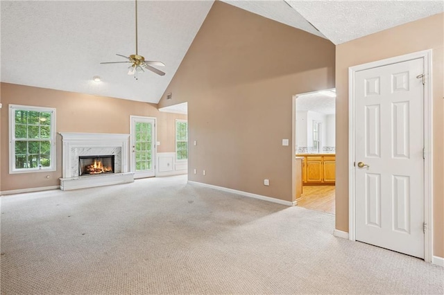 605 Pebble Blvd, Covington, GA 30016 - unfurnished living room with light colored carpet, ceiling fan, high vaulted ceiling, baseboards, and a premium fireplace