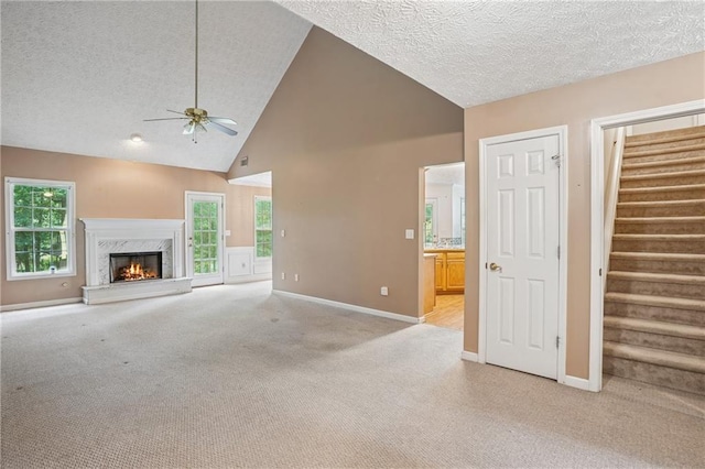 605 Pebble Blvd, Covington, GA 30016 - unfurnished living room featuring a ceiling fan, light colored carpet, a textured ceiling, high vaulted ceiling, and stairs