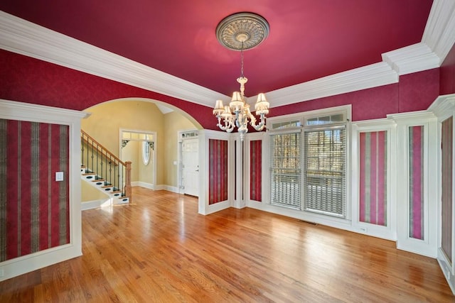 interior space featuring wood-type flooring, ornamental molding, and a notable chandelier