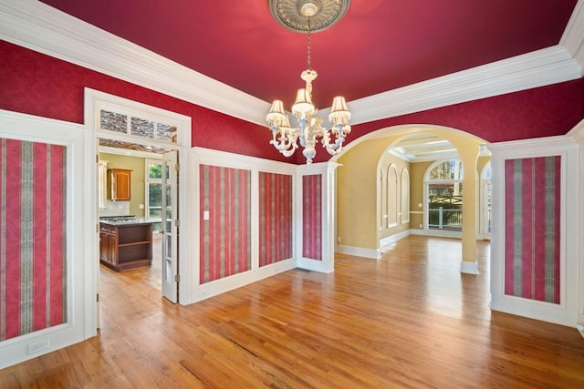 unfurnished dining area featuring a notable chandelier, light hardwood / wood-style floors, and ornamental molding