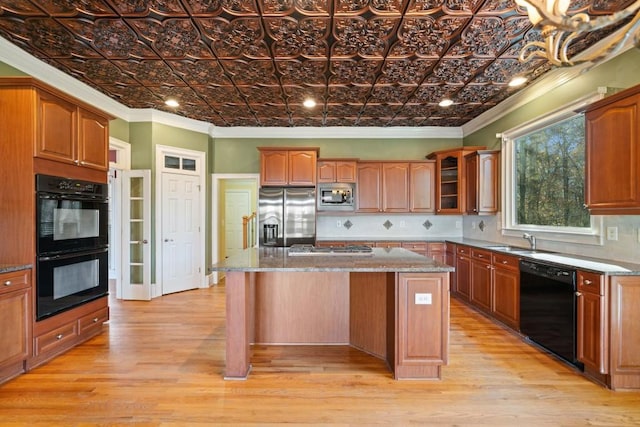 kitchen featuring a center island, light hardwood / wood-style floors, crown molding, and black appliances