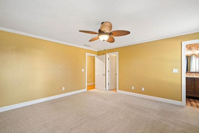 empty room featuring crown molding, sink, ceiling fan, and light colored carpet